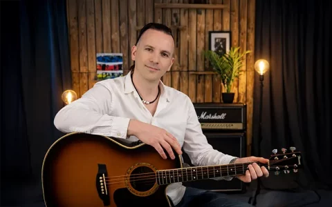 Wouter Baustein met akoestische gitaar in de studio voor privé gitaarlessen en coaching
