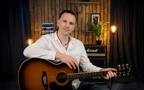 Wouter Baustein met akoestische gitaar in de studio voor privé gitaarlessen en coaching
