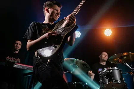 Gitarist op podium met band en kleurrijke lichten – speel muziek in plaats van alleen oefeningen